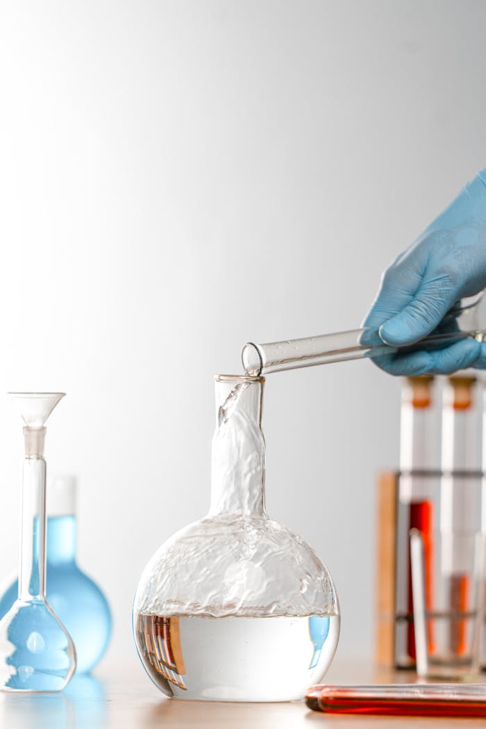 Person Pouring Water in Flat Bottomed Flask